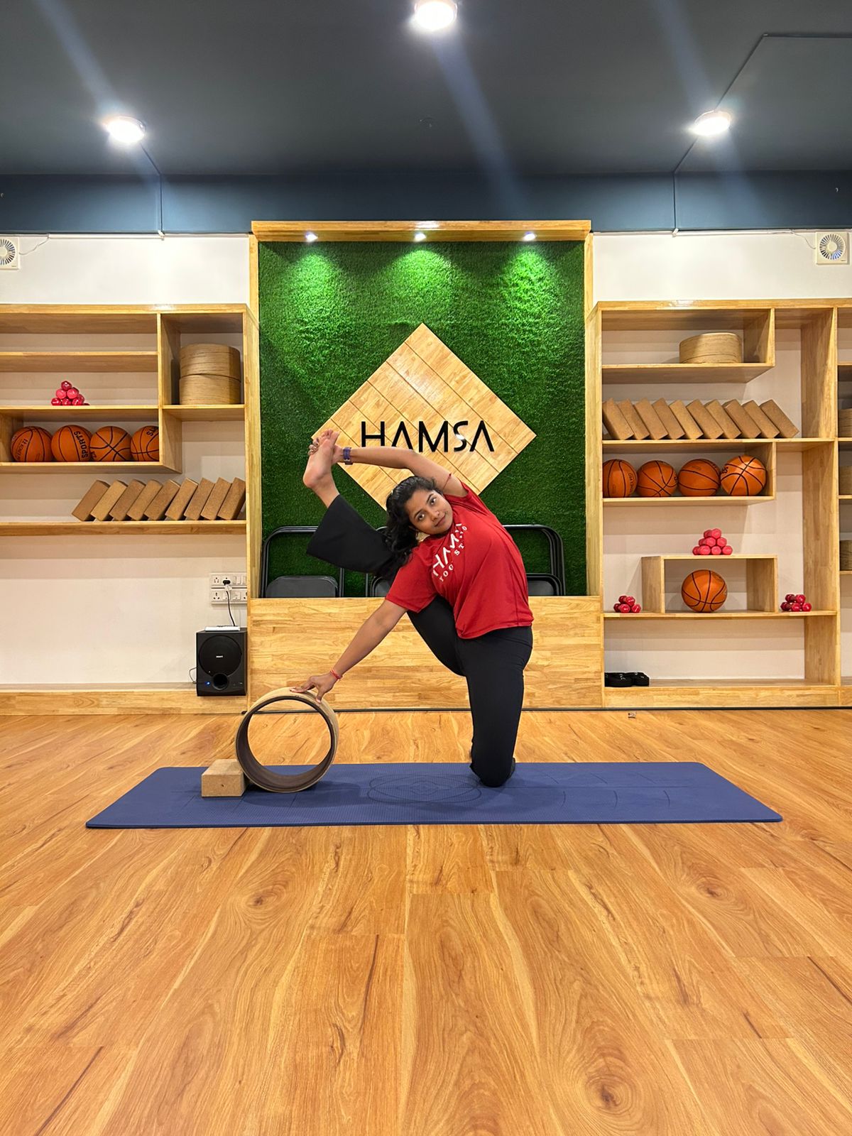 Kneeling side bend supported by a yoga wheel at Hamsa